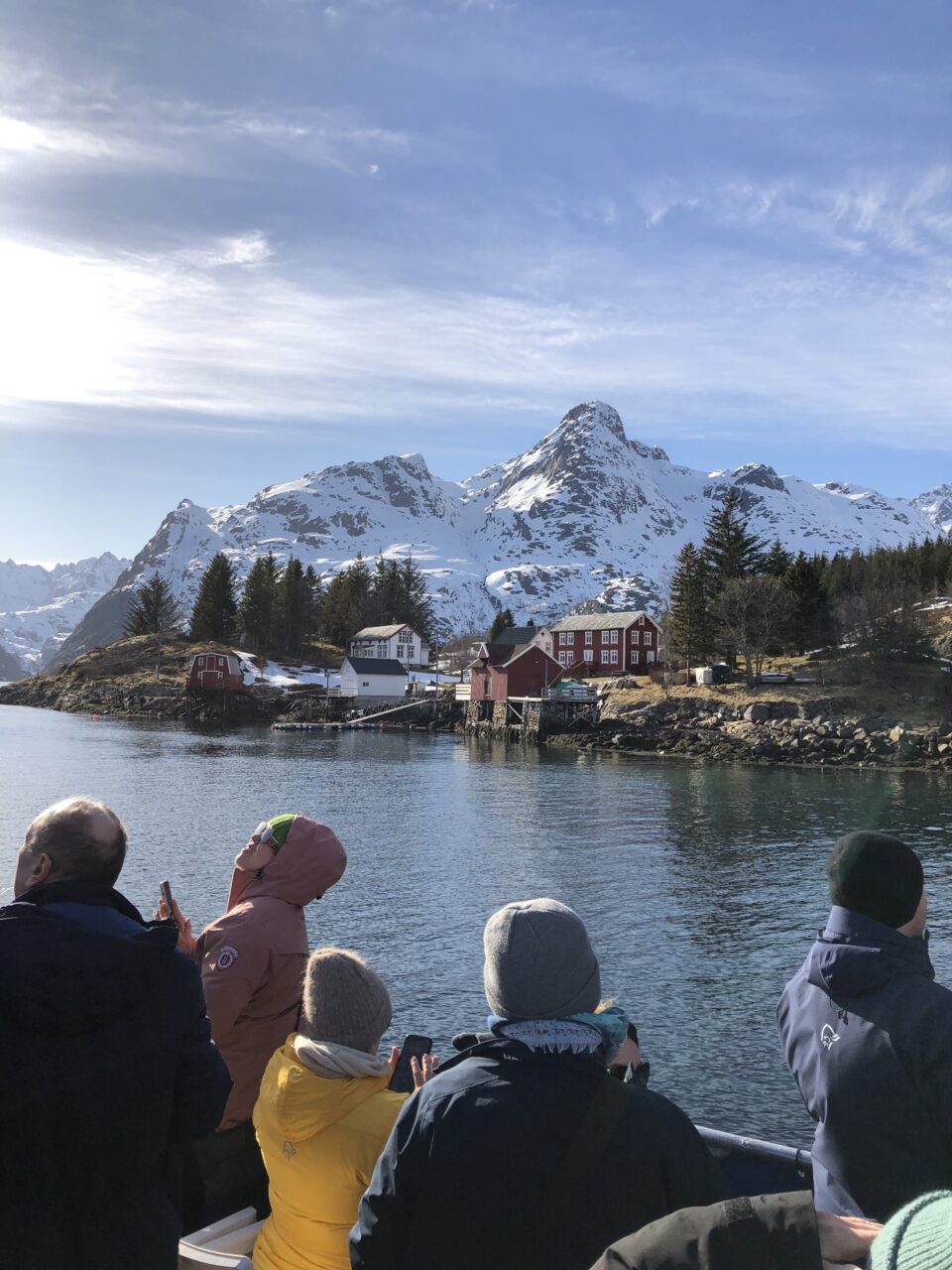 Mennesker på båt står og ser ut mot land. Foto