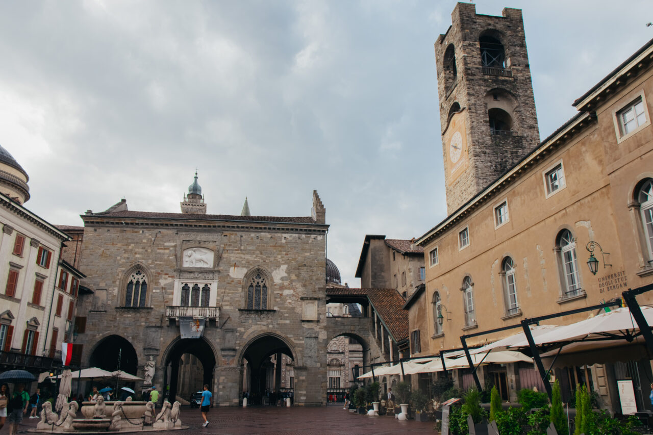 Foto av Piazza Vecchia, et torg i Bergamos gamleby omkranset av en kirke med et høyt tårn. Foto