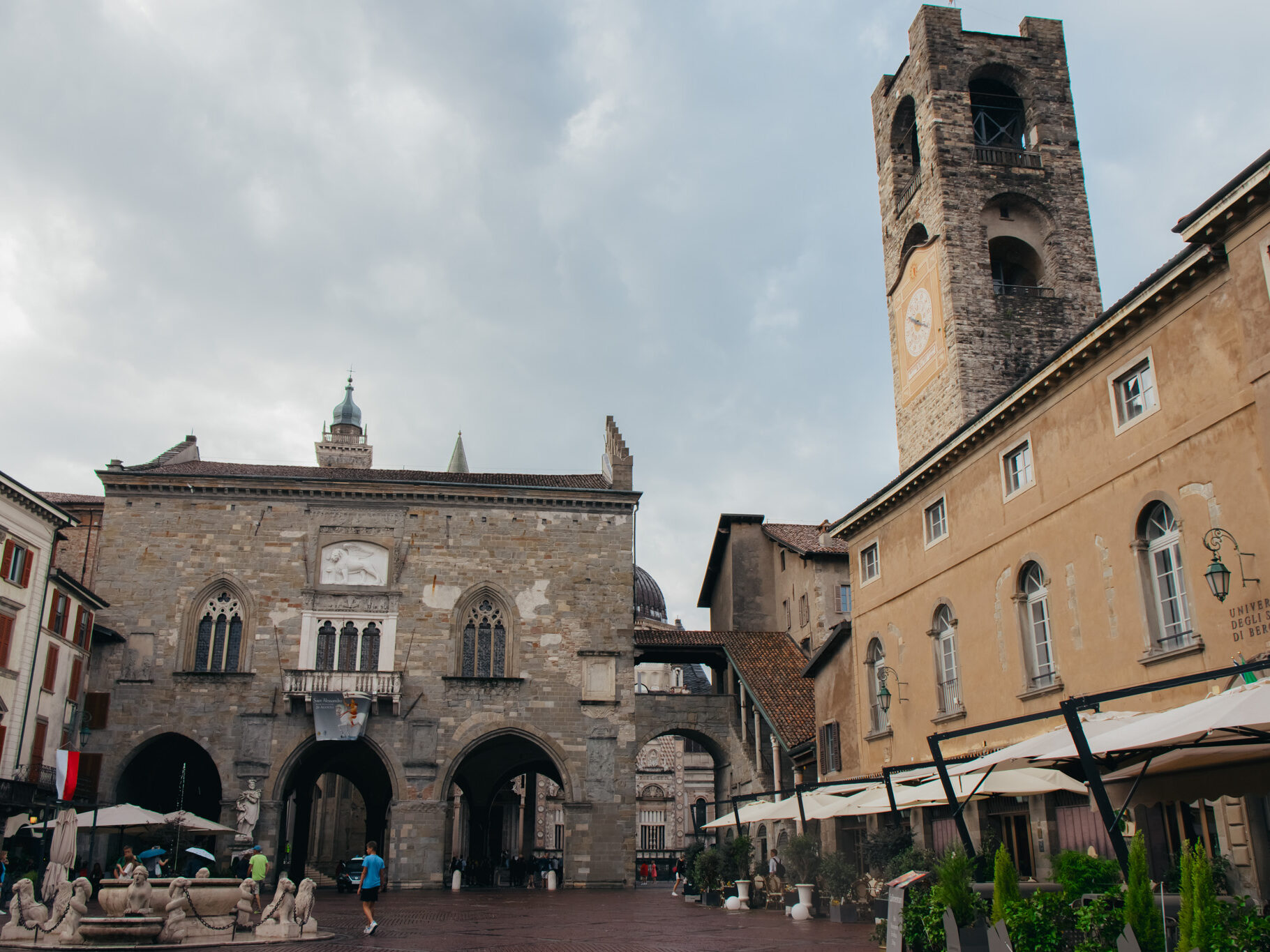 Piazza Vecchia, et torg i Bergamos gamleby omkranset av en kirke med et høyt tårn. Foto