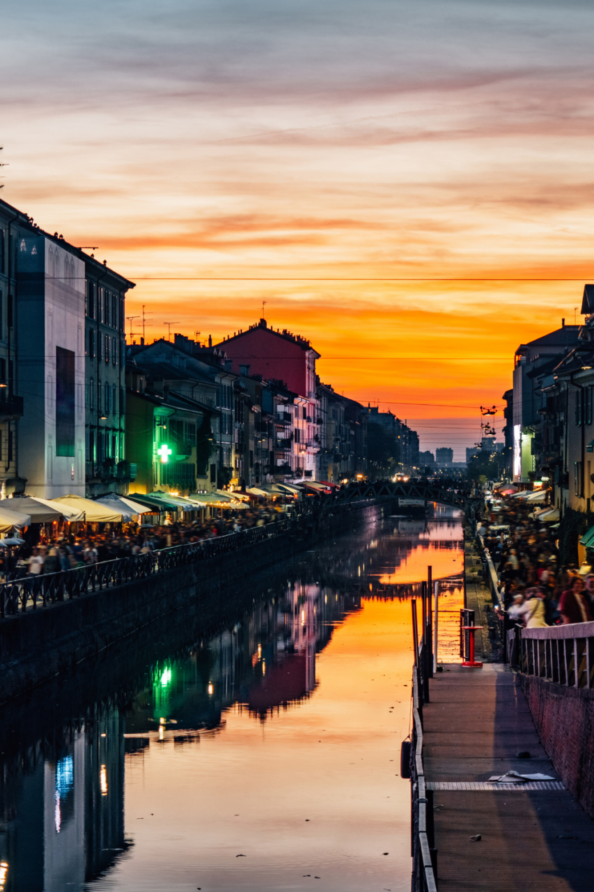 En lang kanal med restauranter og barer på hver side fotografert i solnedgang. Foto