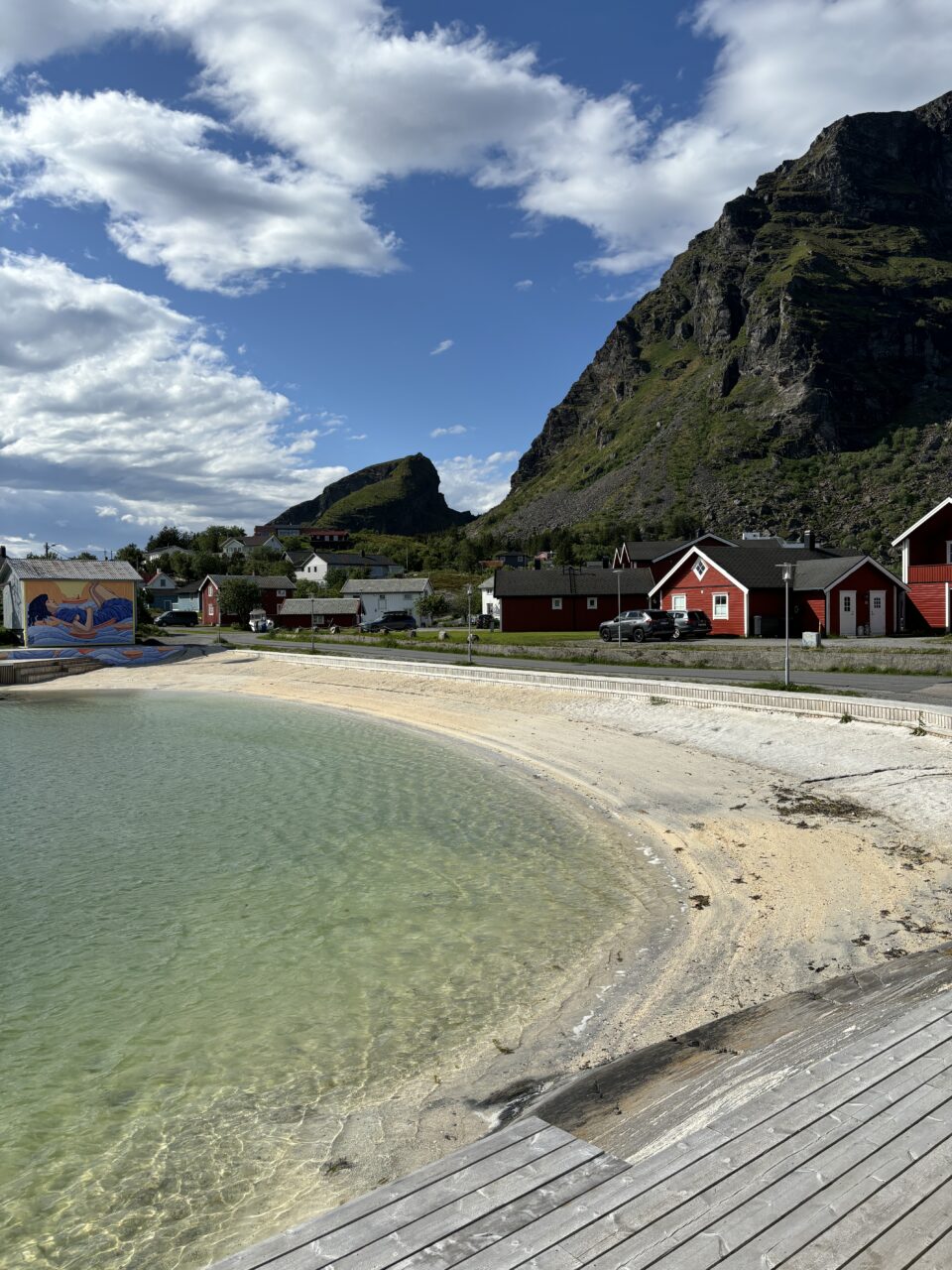 Vik med sandstrand og fjell i bakgrunnen. Foto