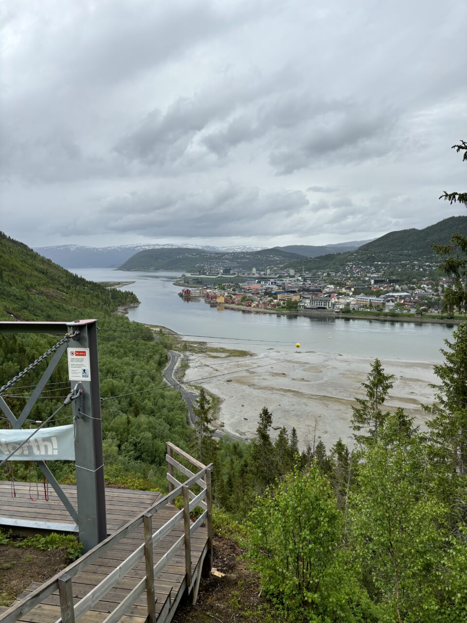 Zipline som går fra en bakketopp og ned i liten by. Foto