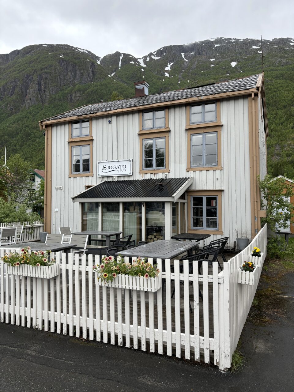 Hvitt gammelt trehus med stakittgjærde. Foto