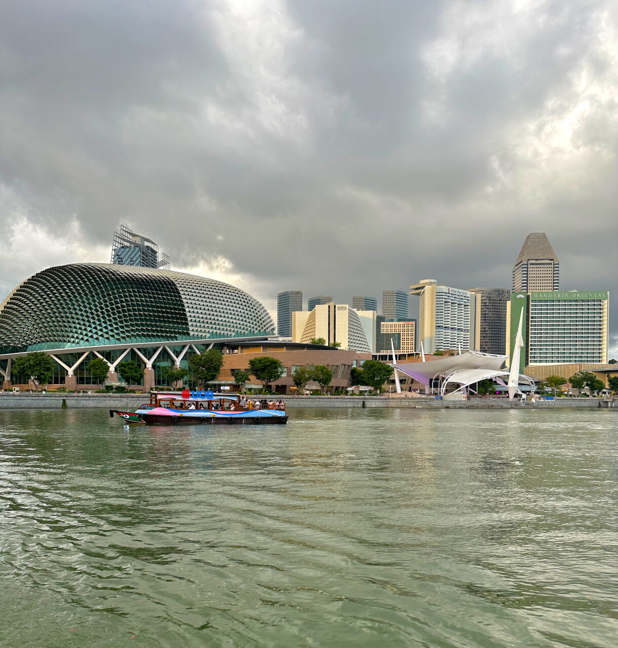 Utsikt over Singapore-elven med et elvecruise foran Esplanade-teatret og moderne skyskrapere i bakgrunnen. Foto